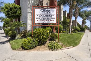A sign for Topanga Terrace Apartments is displayed in front of a building.